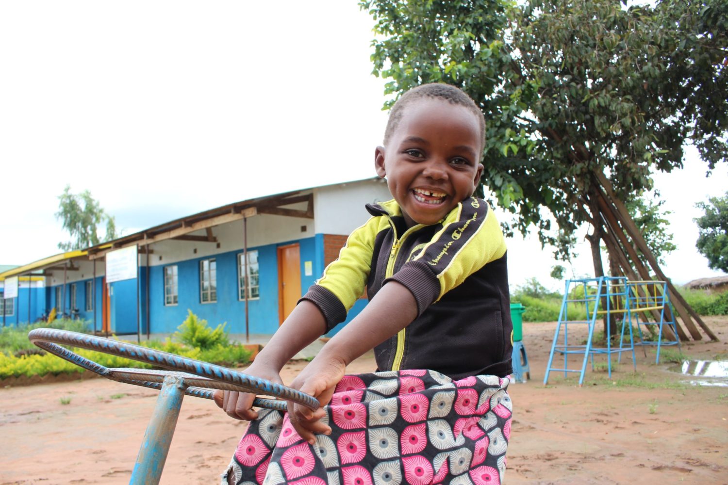 photo of a boy in Malawi sitting on a bicycle and smiling