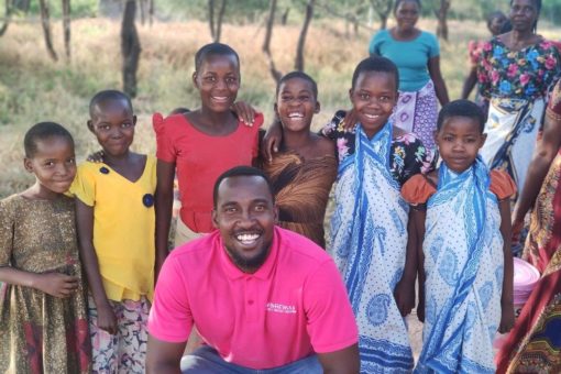 photo of Sanku representative with group of children dressed in bright colors smiling